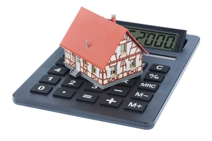 Une calculatrice posée sur des plans de maison, symbolisant le calcul des coûts et des aides.